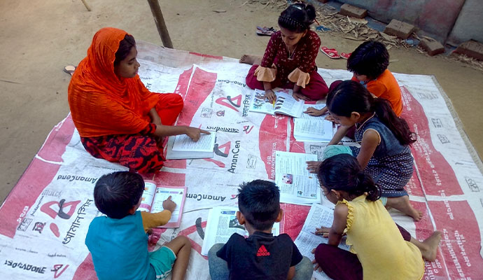 Older student guiding younger children in peer learning and reading from textbooks