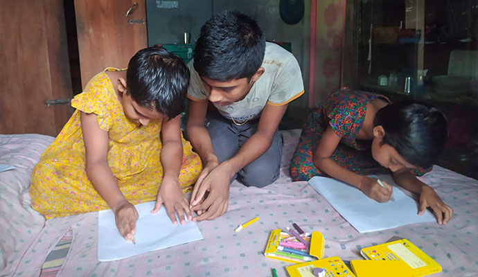 Children gathered on a bed sketching and drawing with colorful art supplies