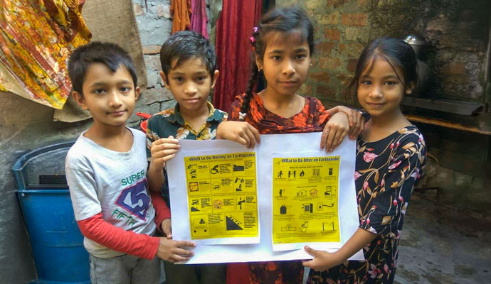 Four children holding informational posters on earthquake safety precautions and response