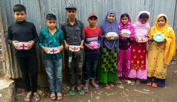 Students lined up holding handmade first aid medical kit boxes with red crosses