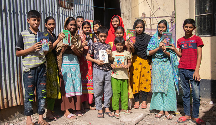 Group of smiling children holding colorful storybooks from a community mobile library