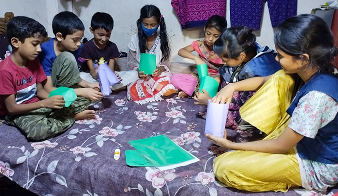 Children sitting on a mat folding and crafting colorful paper boxes in an origami session