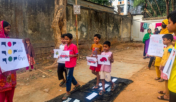 Children holding traffic sign posters and practicing safe road crossing on a simulated zebra crossing