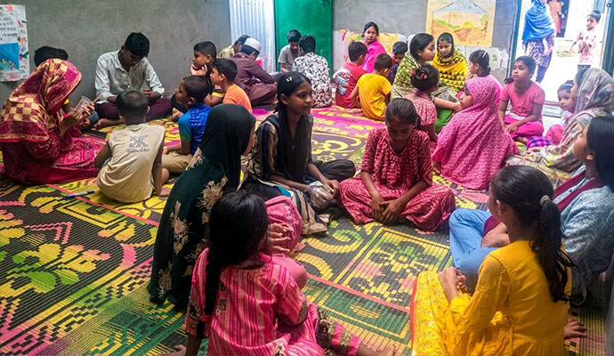 Children and teachers gathered on floor mats during an educational learning session