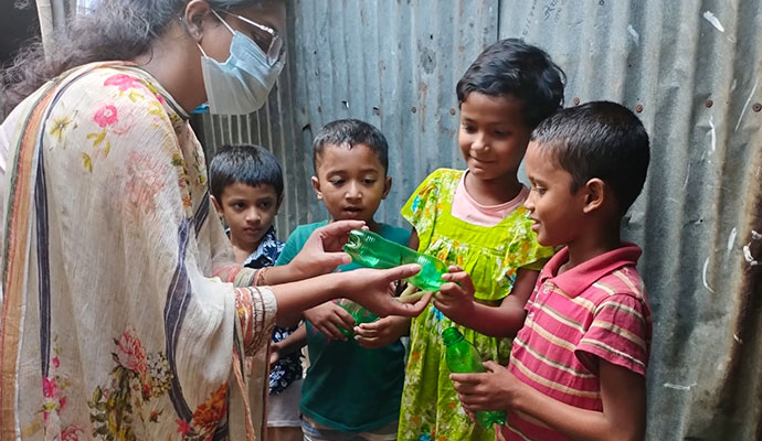 Instructor showing children how to repurpose and craft with green plastic bottles