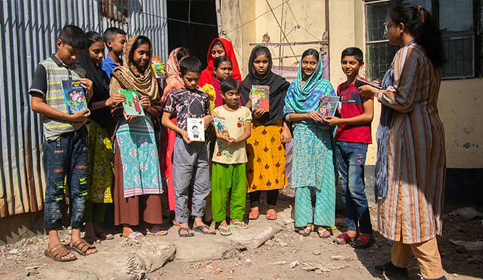 Community coordinator with a notebook speaking with students holding reading books