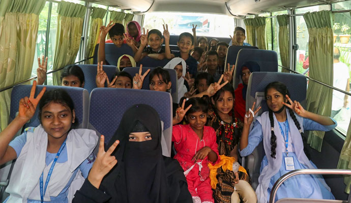Smiling students making peace signs aboard an educational excursion bus during a landmark tour