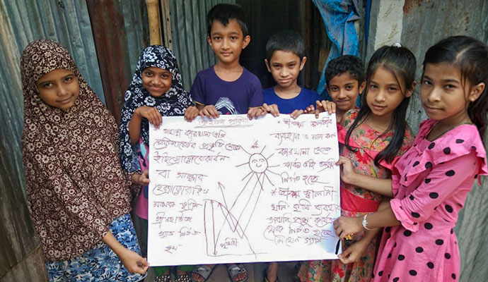 Children holding a handwritten poster illustrating the greenhouse effect and global warming