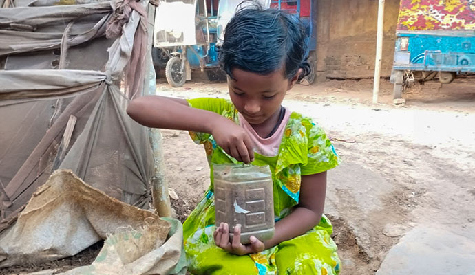 Young girl placing soil and organic materials into a recycled container for composting